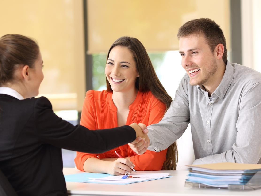 image of a couple smiling and the man shaking hands with a saleswoman